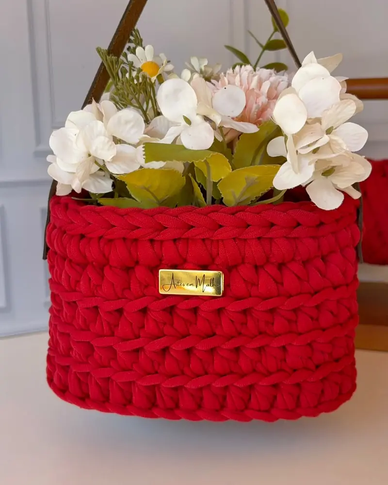 Cesto suspenso de crochê vermelho com flores brancas e plaquinha dourada